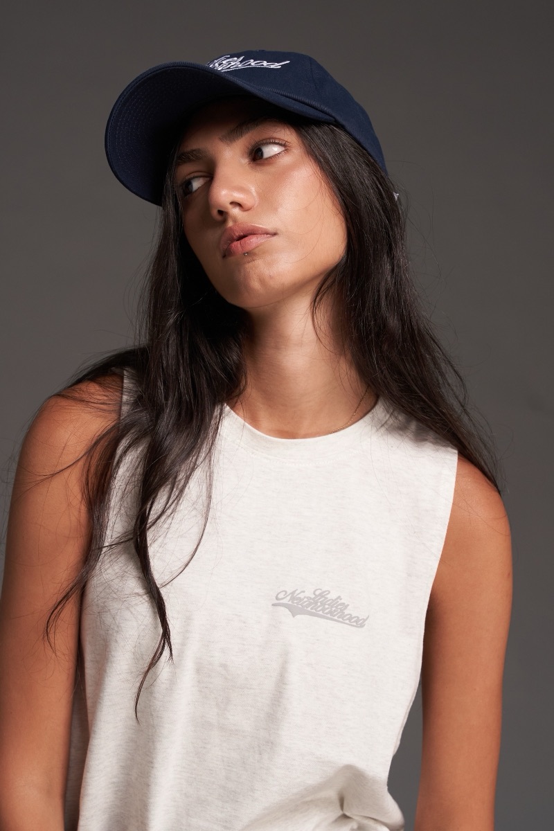 Model in a white Ladies Neighborhood top and navy cap